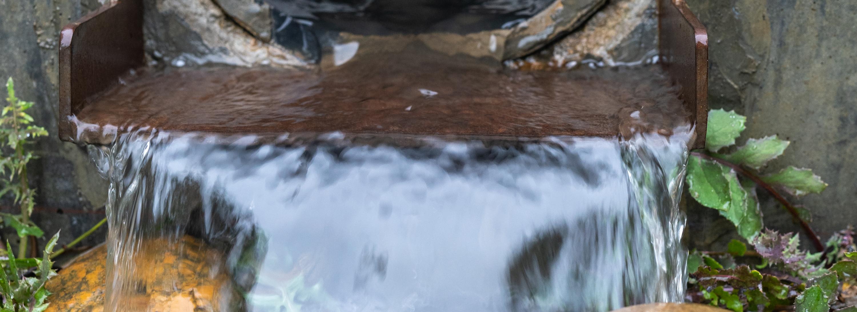 Close-up of water flowing out of a storm drain over rocks. Photo: Shira Bezalel