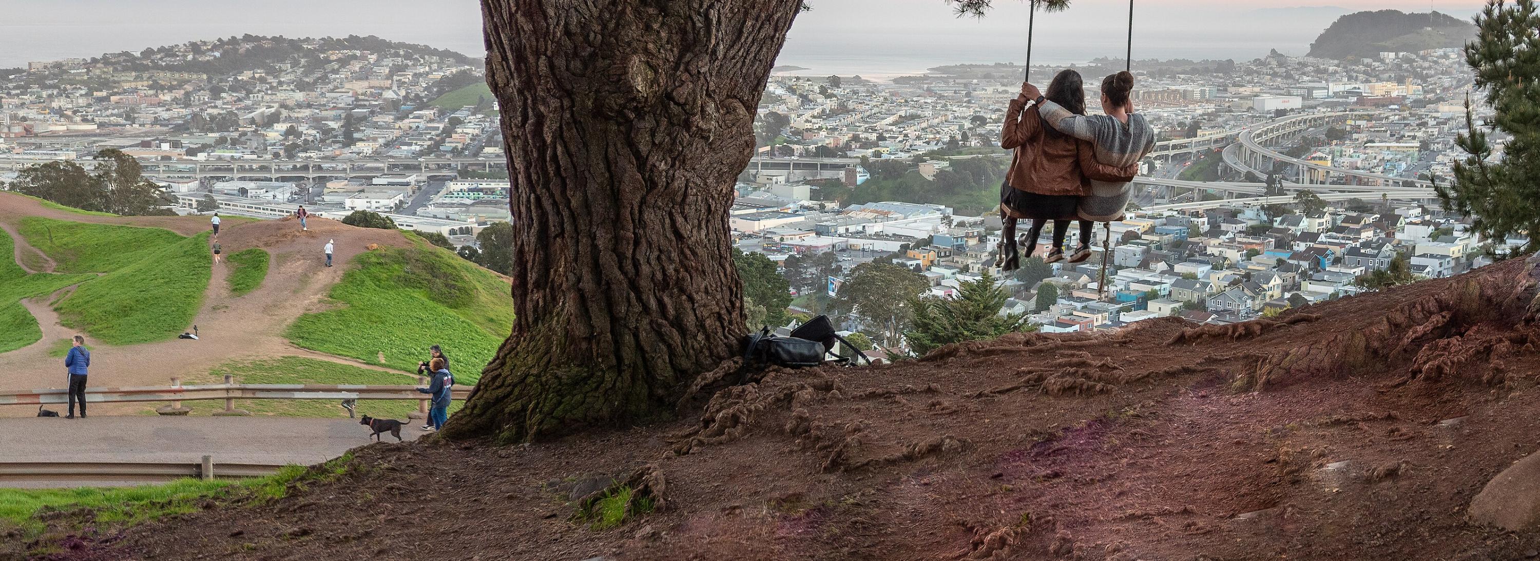 Two people in a swing over looking the city.