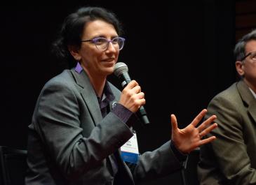 Close-up of Ezra Miller seated and holding a microphone while gesturing with other hand and smiling.
