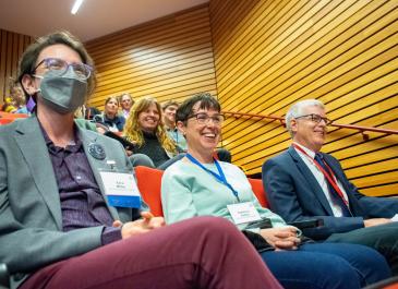 From left to right, Ezra Miller, Rebecca Sutton, and Jay Davis laugh in the audience.
