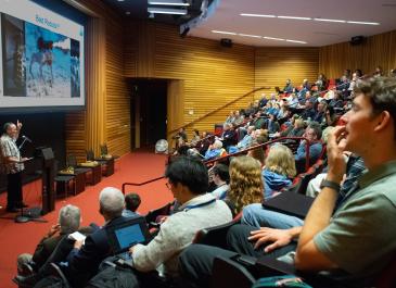 Don Yee points upwards towards a slide titled "Bad Robots" as a large audience watches.