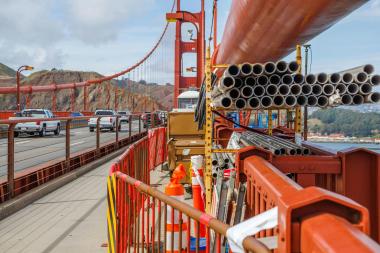 Construction on the Golden Gate bridge with cars passing by in the background