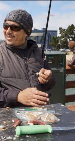Smiling Anthony Khalil baits a hook during a morning fishing session at Mission Rock pier.