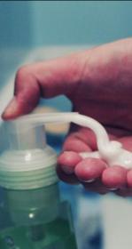 Hand depressing a bathroom soap pump