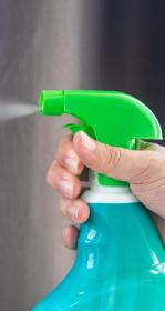 Close up of hand spraying disinfectant from a blue bottle