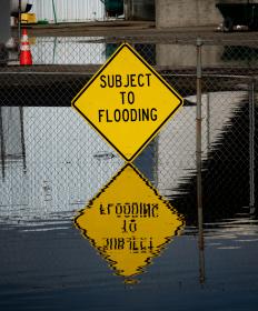 Subject to flooding yellow road sign reflected in floodwaters that reach the sign's bottom