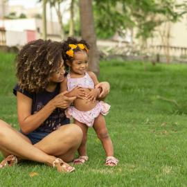 Mother and daughter sitting on grass. Credits to Orione Conceição.